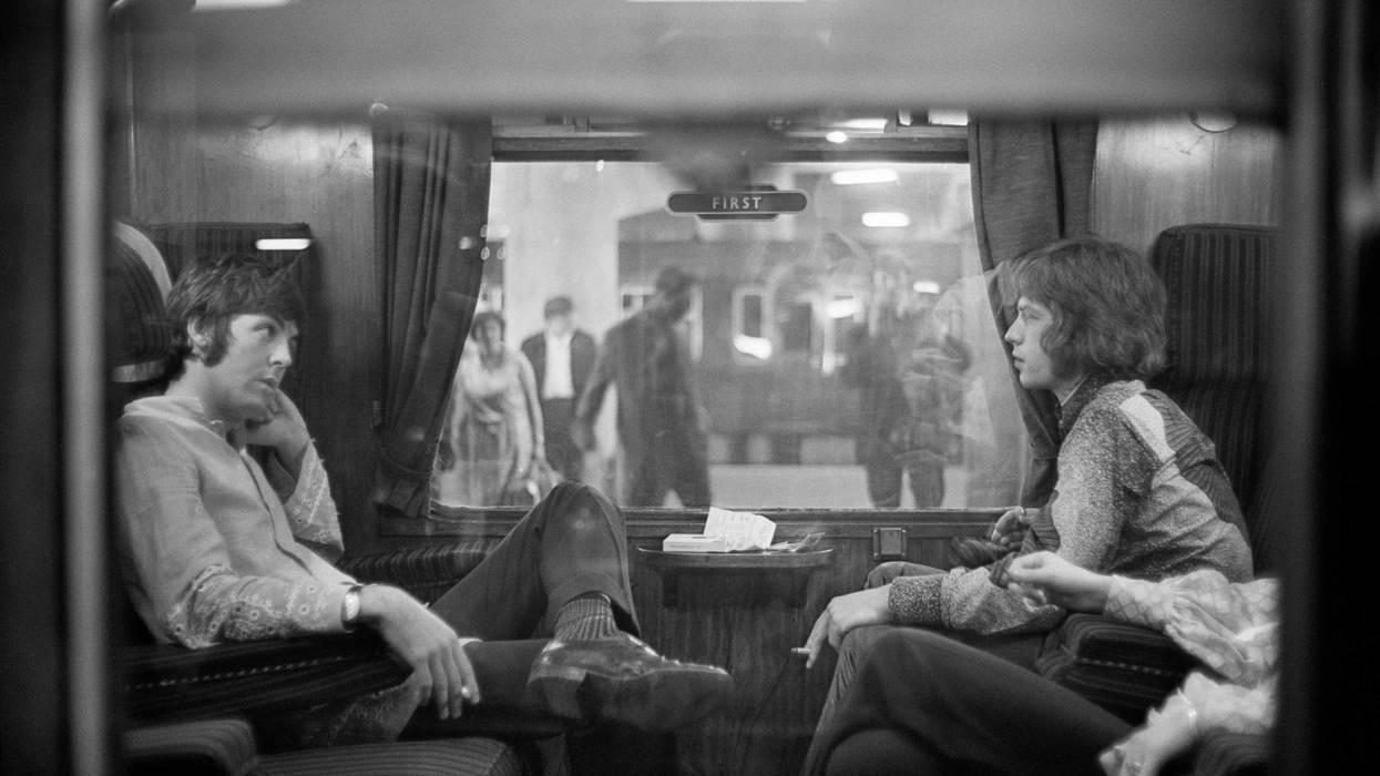 25th August 1967: Paul McCartney of the Beatles and Mick Jagger of the Rolling Stones sit opposite each other on a train at Euston Station, waiting for departure to Bangor. (Photo by Victor Blackman/Express/Getty Images)