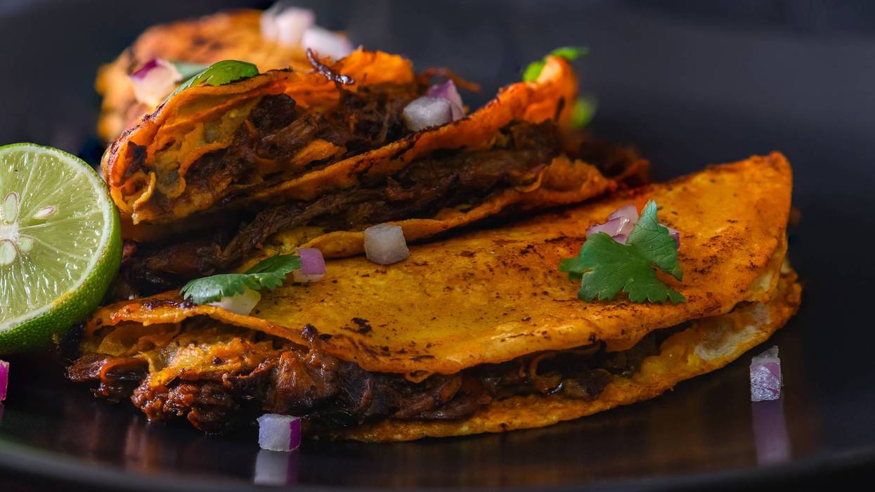 3 Beef Birria Tacos Stacked on Black Plate