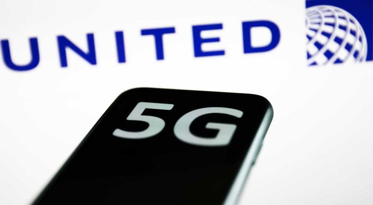 5G sign displayed on a phone screen and United Airlines logo displayed on a screen in the background are seen in this illustration photo taken in Krakow, poland on January 18, 2022.