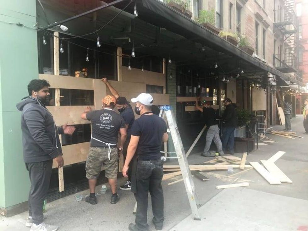 7:40 p.m. Restaurant workers board up the windows of an eatery on the Lower East Side.