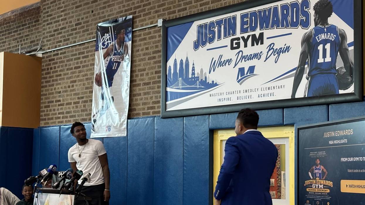 76ers forward Justin Edwards (left) helps unveil the sign naming Mastery Charter Smedley Elementary School's gym after him.