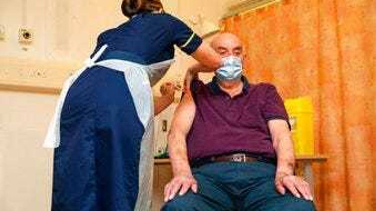 82-year-old Brian Pinker receives the Oxford University/AstraZeneca COVID-19 vaccine from nurse Sam Foster at the Churchill Hospital in Oxford, England, Monday, Jan. 4, 2021. (Steve Parsons/Pool Photo via AP)