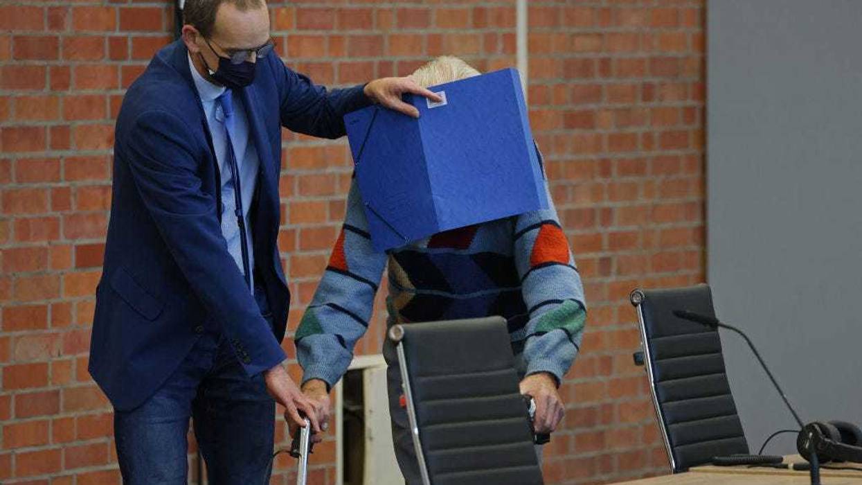 A 100-year-old man accused of being a former Nazi-era concentration camp guard is assisted by his lawyer as he arrives for the first day of his trial in accessory to the murder of 3,500 people on October 07, 2021 in Brandenburg, Germany. The man is accused of having worked as a guard at the Sachsenhausen concentration camp near Berlin from 1942 to 1945 during World War II, where prisoners, including Jews, captured Soviet soldiers and political dissidents, were systematically mistreated and murdered. (Photo by Sean Gallup/Getty Images)