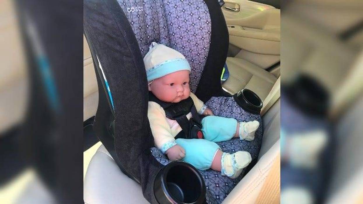 A baby doll in a rear facing car seat in vehicle