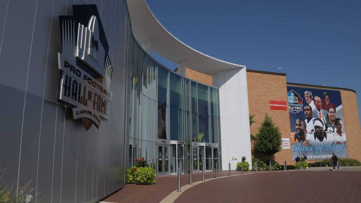 A banner featuring 2019 inductees Champ Bailey and Pat Bowlen and Gil Brandt and Tony Gonzalez and Ty Law and Kevin Mawae and Ed Reed and Johnny Robinson hangs outside the Pro Football Hall of Fame.