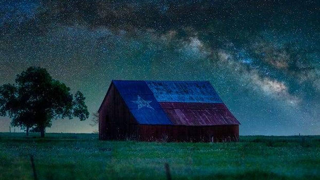 A barn painted with a Texas flag at night