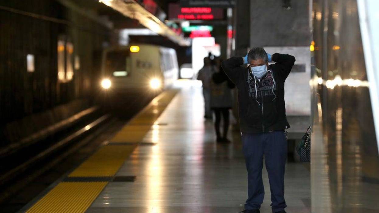 A Bay Area Rapid Transit (BART) passenger adjusts his protective mask as a train pulls into the Balboa Park station on April 08, 2020 in San Francisco, California.