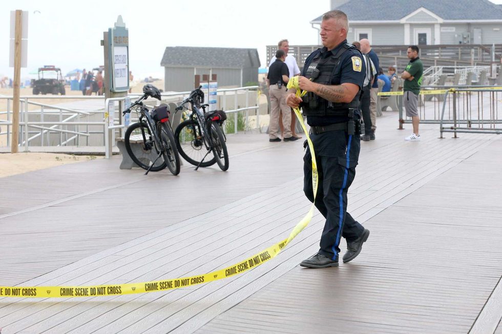 A Belmar police officer wrap up crime scene tape that spanned the boardwalk near where a person drowned in the ocean adjacent to the 8th Avenue beach jetty in the town Monday afternoon, June 13, 2022