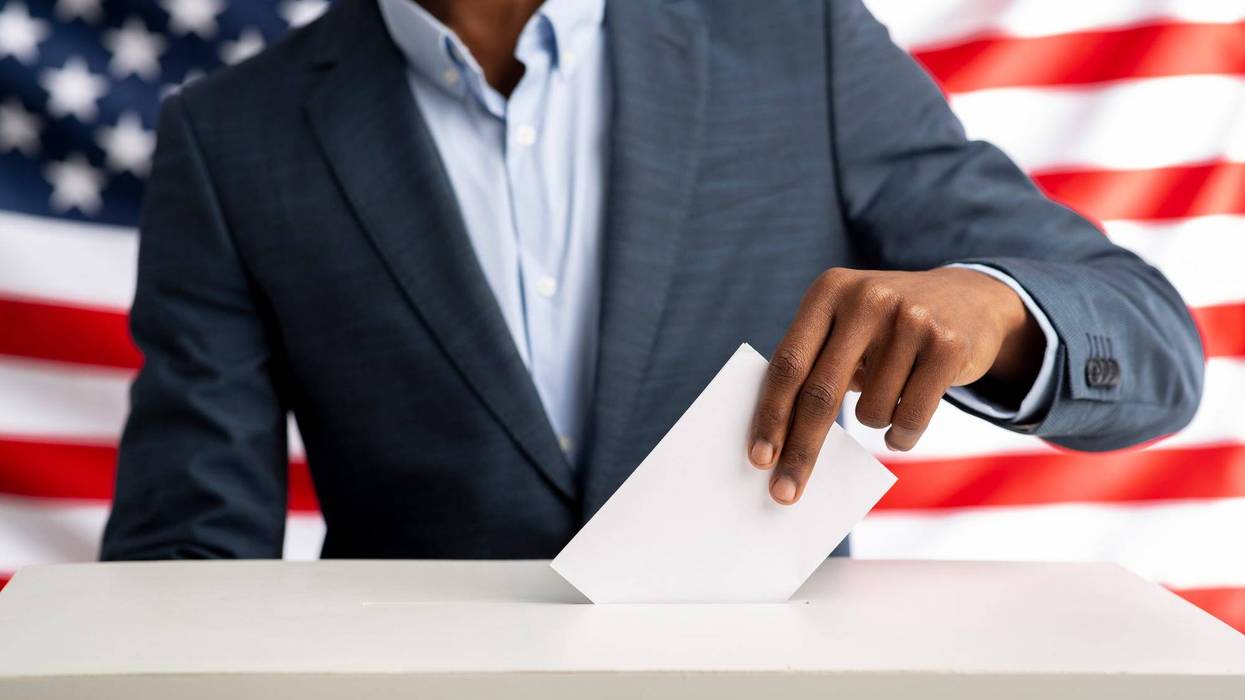 A Black man votes at the ballot box