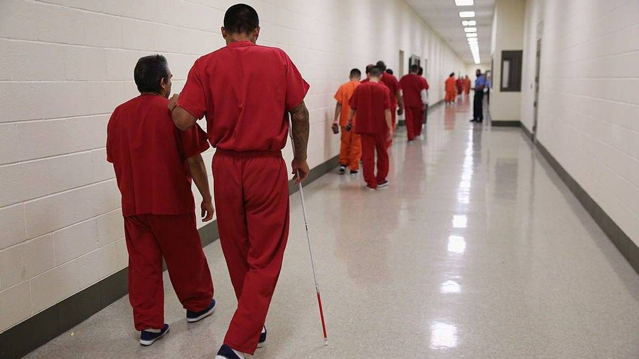 A blind detainee walks with a fellow immigrant at the Adelanto Detention Facility