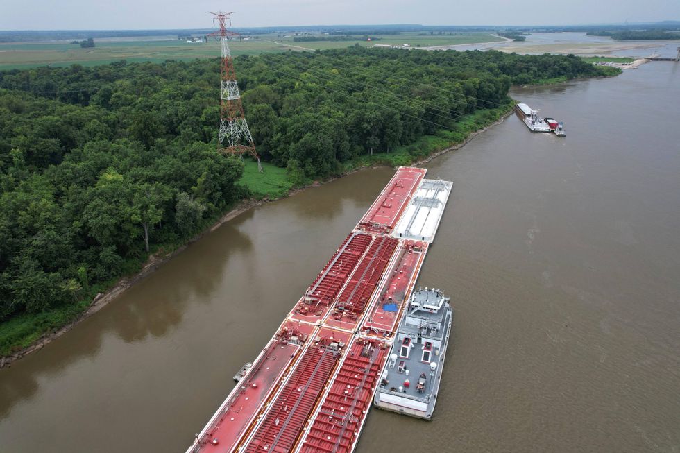 A blue tarp covers the wreckage of a helicopter after it clipped a power line spanning the Mississippi River and crashed onto a barge Thursday, Aug. 7, 2025, in East Alton, Ill.