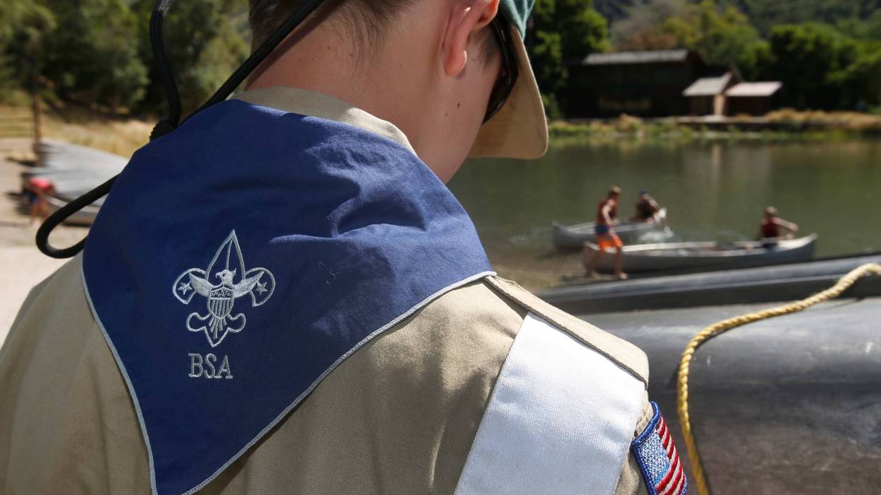 A Boy Scout works on a canoe at camp.