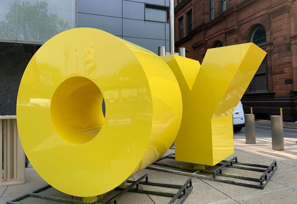 A bright yellow statue of the word "OY." But from the other side, it reads "YO."