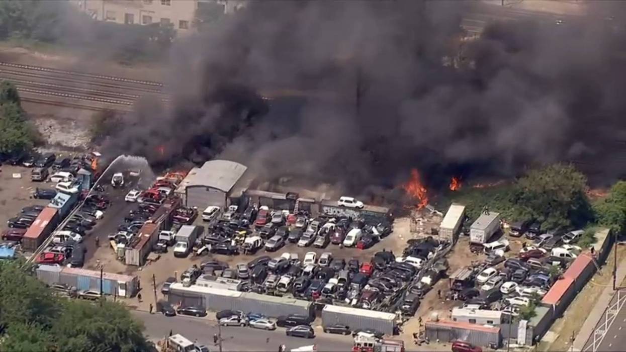 A brush fire burns between a junkyard and train tracks in North Philadelphia.