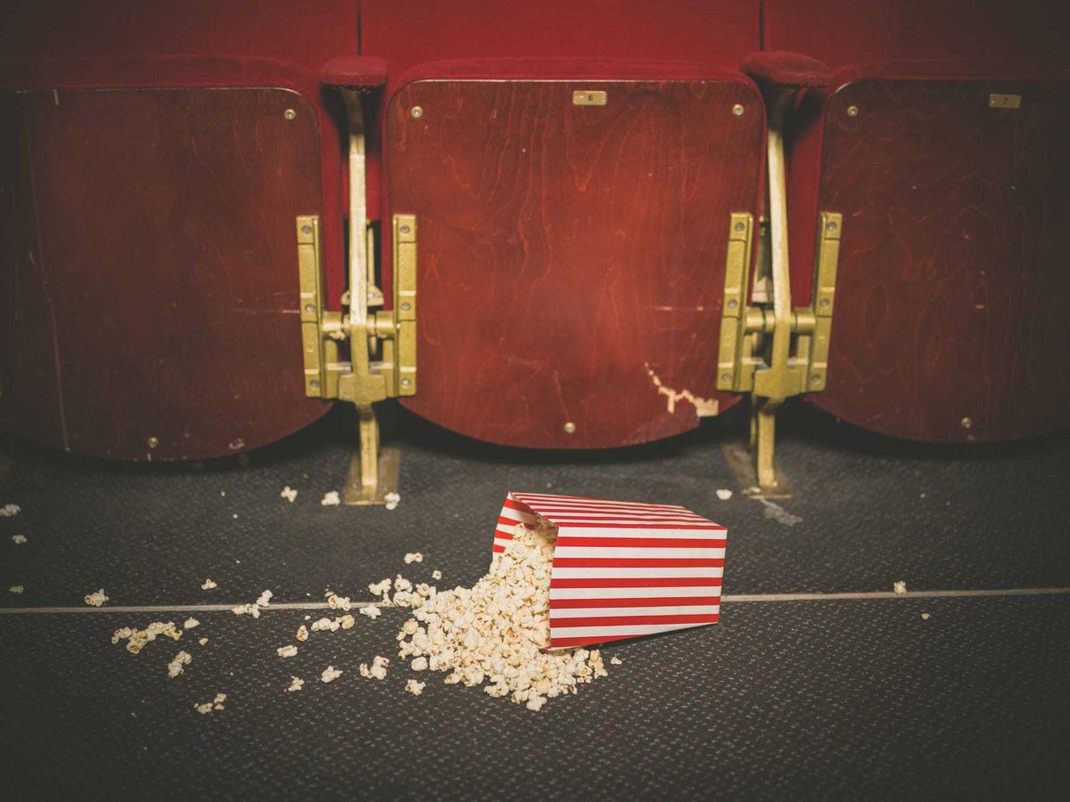 A bucket of spilled popcorn on the floor of a movie theater.