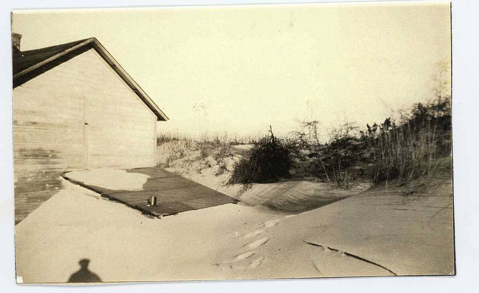 A building is partially buried in the sand in the 1870s