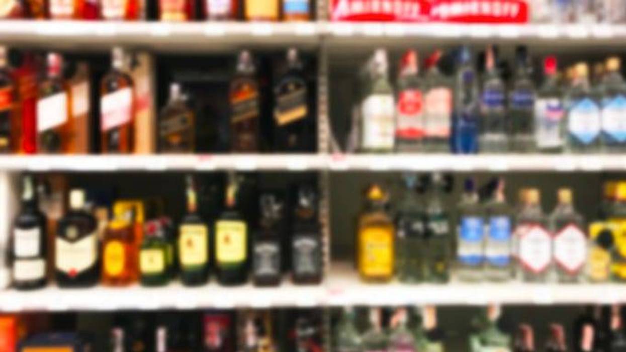 a burred image shows liquor bottles on a store shelf