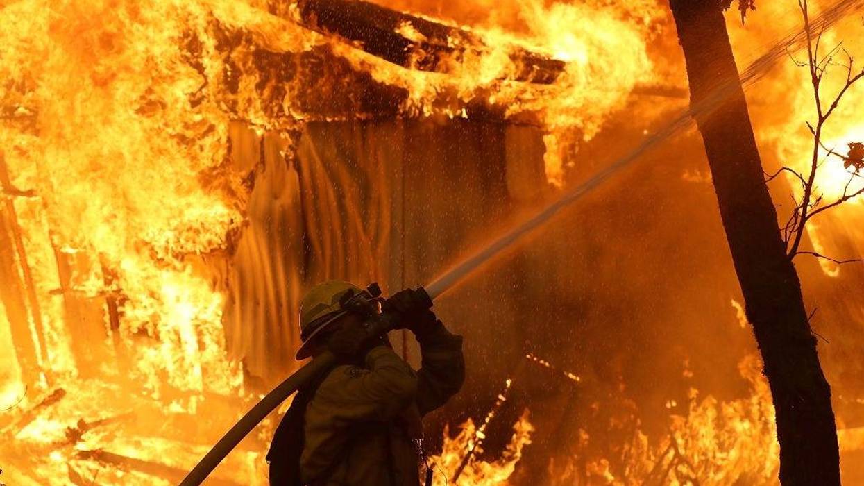 A Cal Fire firefighter monitors a burning home as the Camp Fire moves through the area on November 9, 2018 in Magalia, California.