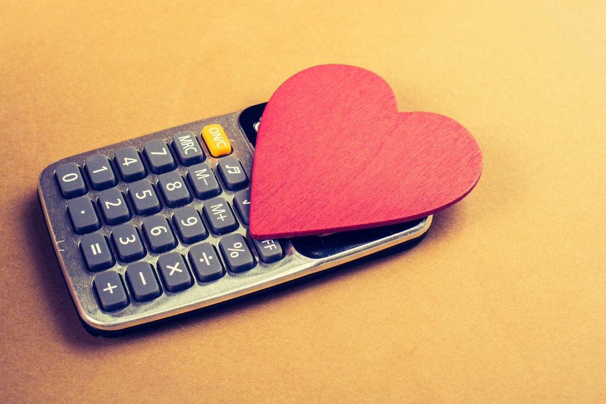 A calculator with a cut-out heart on top of it. Burnt orange background.