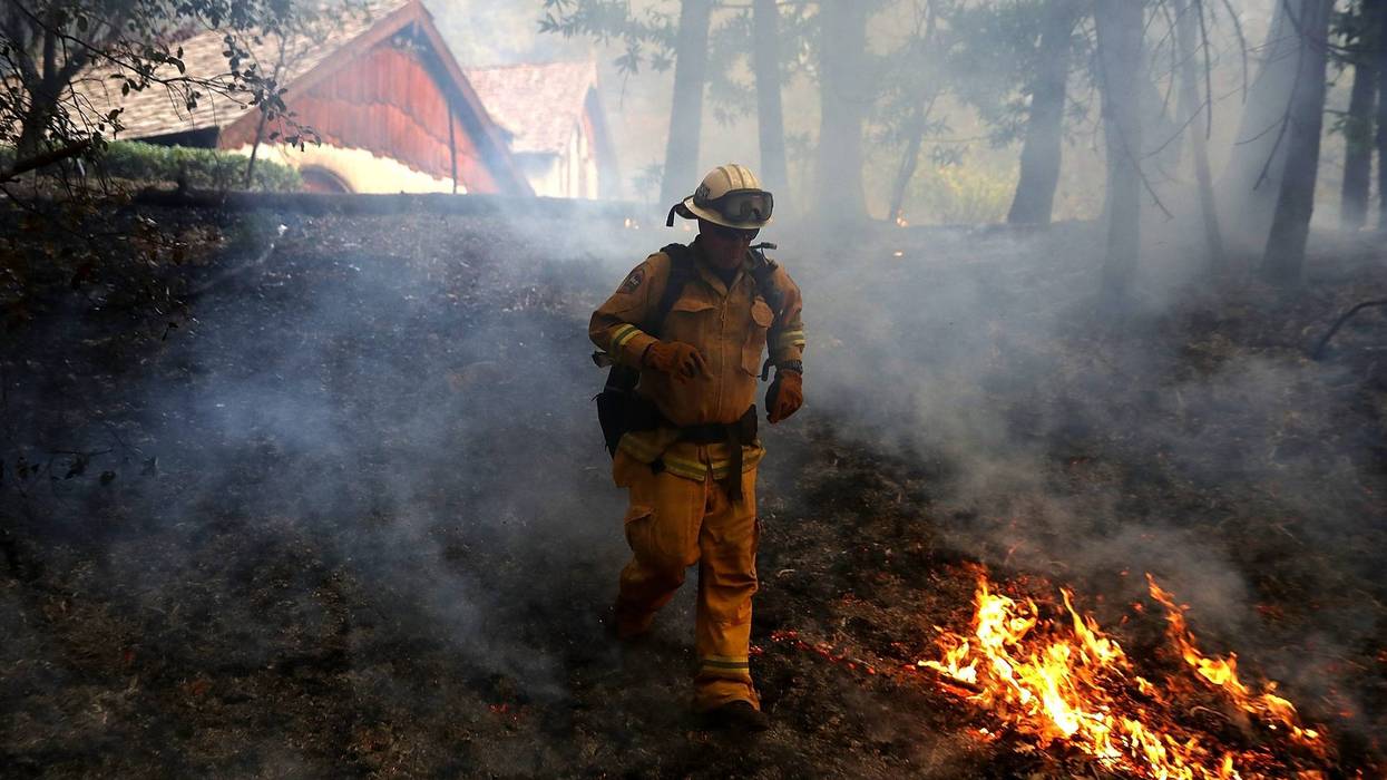: A CalFire chief runs past burning grass during a firing operation while battling the Tubbs Fire on October 12, 2017 near Calistoga, California.