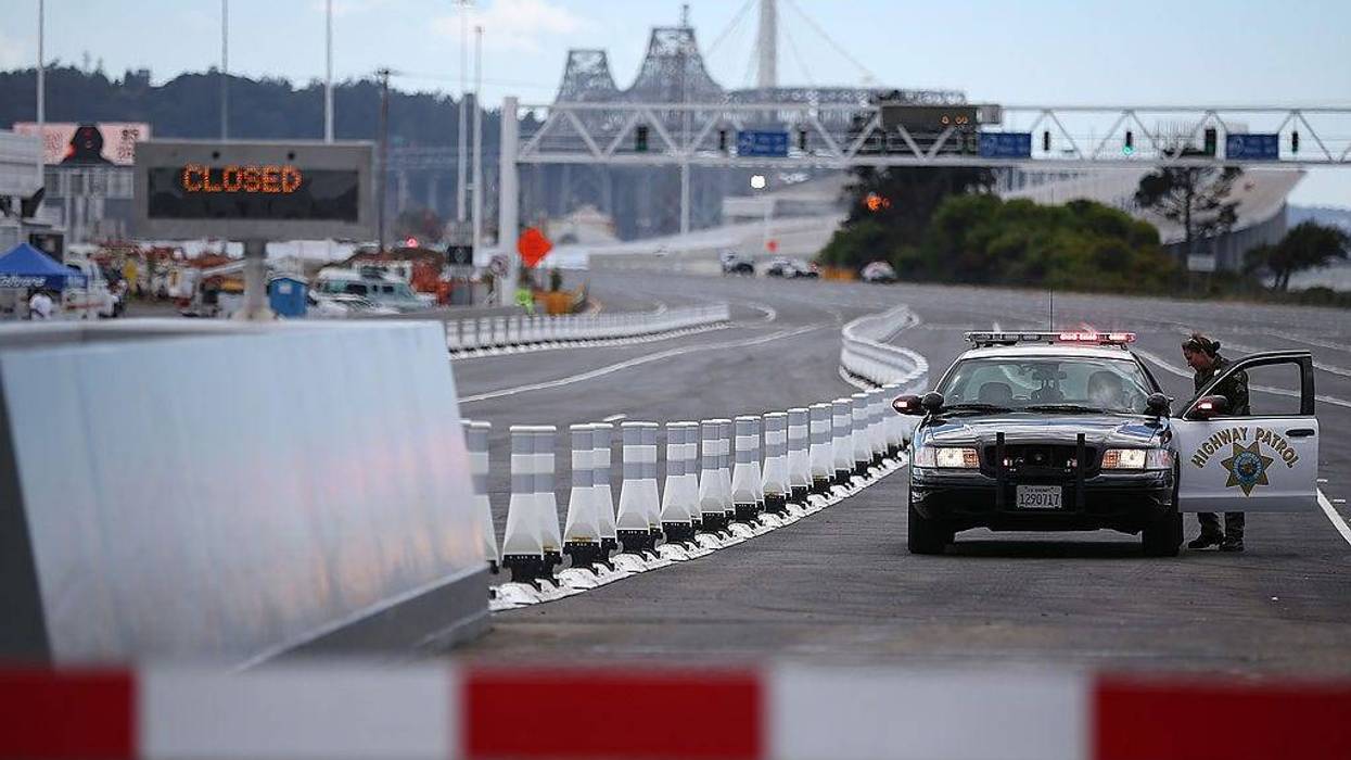 A California Highway Patrol officer blocks a toll plaza lane before a chain-cutting ceremony to officially open the new eastern span of the San Francisco Oakland Bay Bridge on August 30, 2013 in Oakland, California.