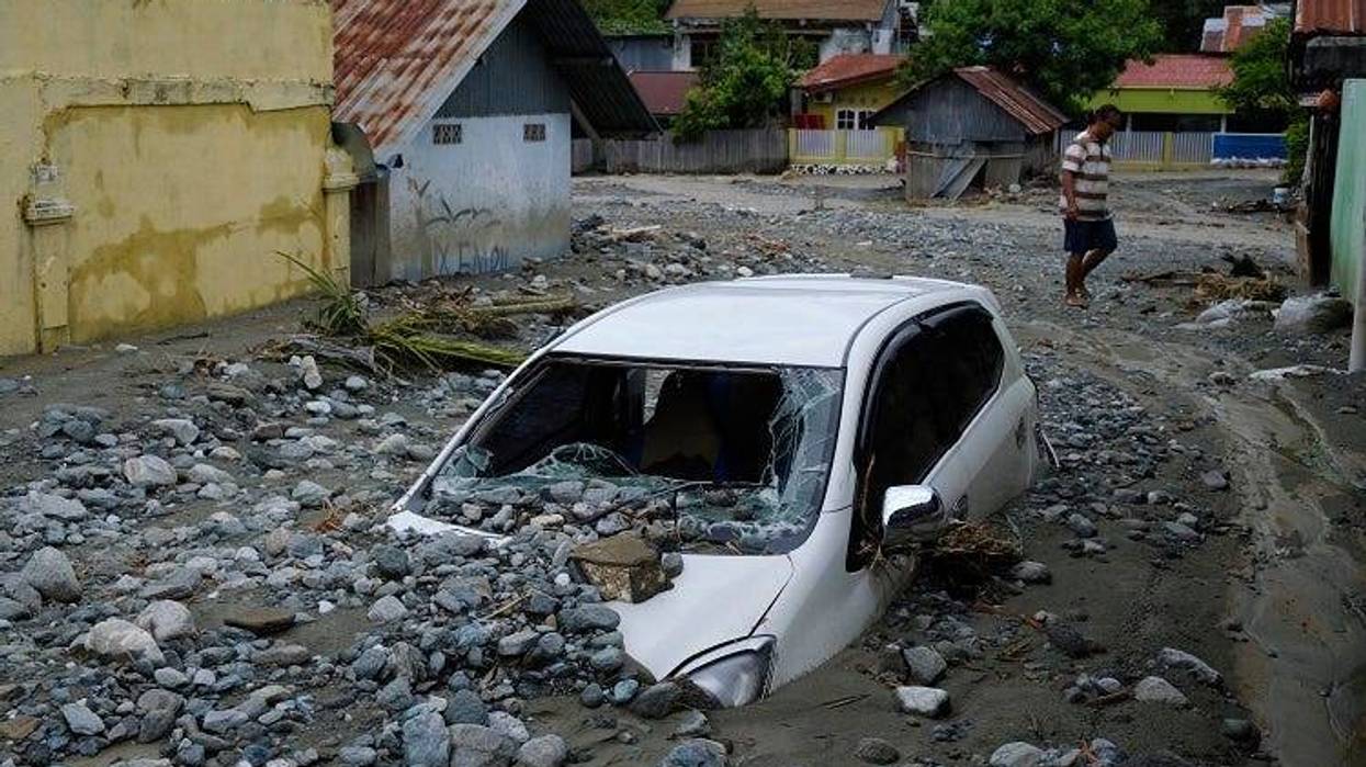 A car sits abandoned in the mud on a flooded street on March 20, 2019 in Sentani, Papua province, Indonesia. At least 104 people have died and nearly 7,000 have been displaced from their homes after three straight days of heavy rain led to massive flash