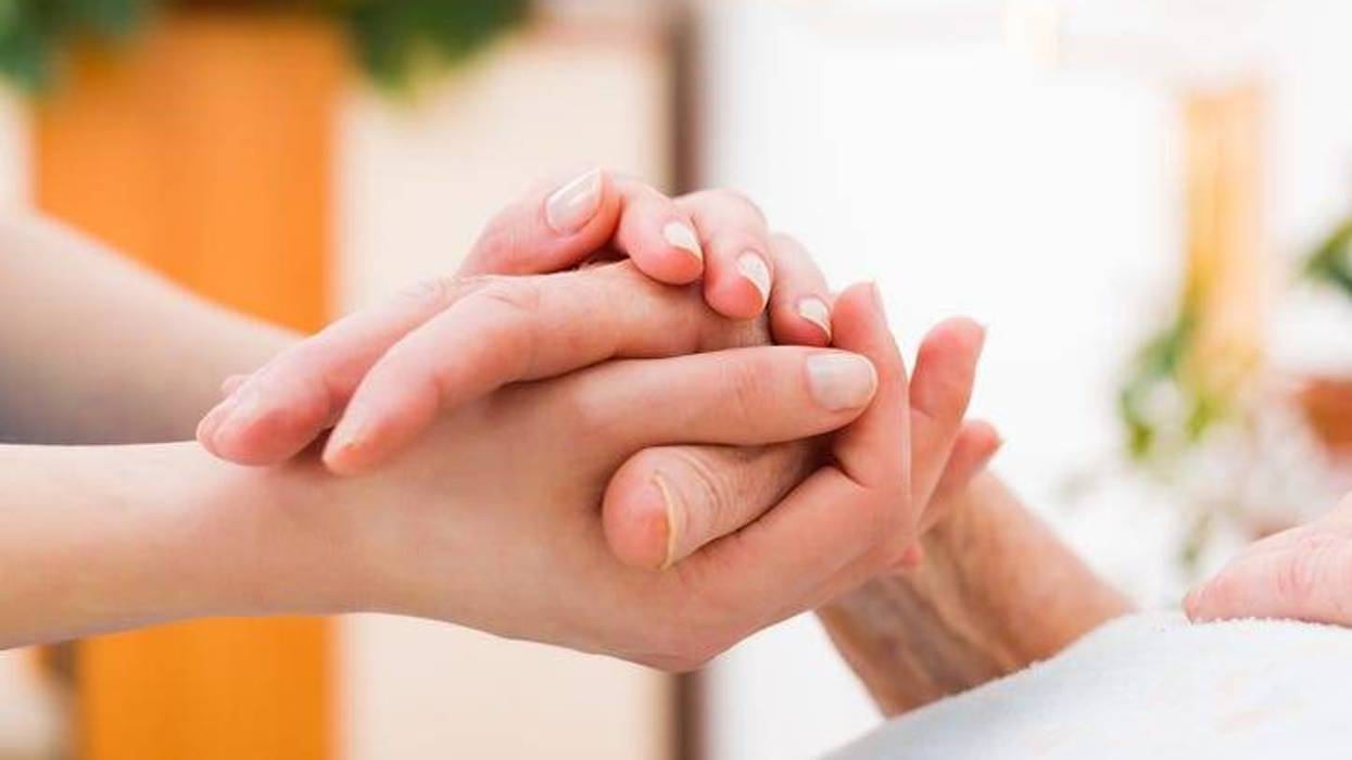 A caregiver holding a person's hand.