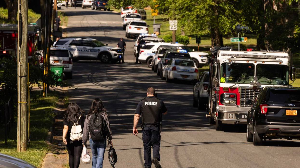 A Charlotte-Mecklenburg Police Department officer, right, escorts two young girls who were trying to get home after school near the scene of a shootout on the 5000 block of Galway Drive in east Charlotte, North Carolina, on Monday, April, 29, 2024.