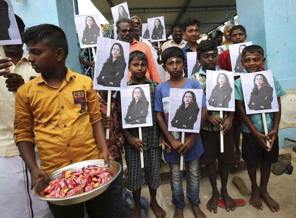 A child holds a tray of chocolates as others hold portraits of U.S. Vice President-elect Kamala Harris after participating in special prayers ahead of her inauguration, at a Hindu temple in Thulasendrapuram, the hometown of Harris