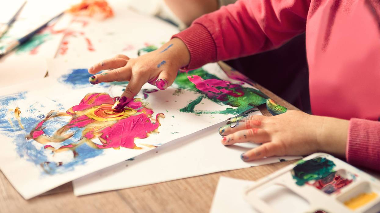 A child uses their fingers to paint.
