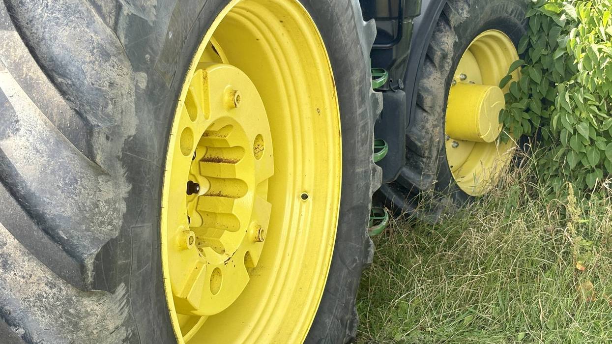 A close-up of a large tractor tire, featuring a distinctive yellow hub and black tread. The rugged design is typical for farm machinery, showcasing strength and durability for agricultural work.