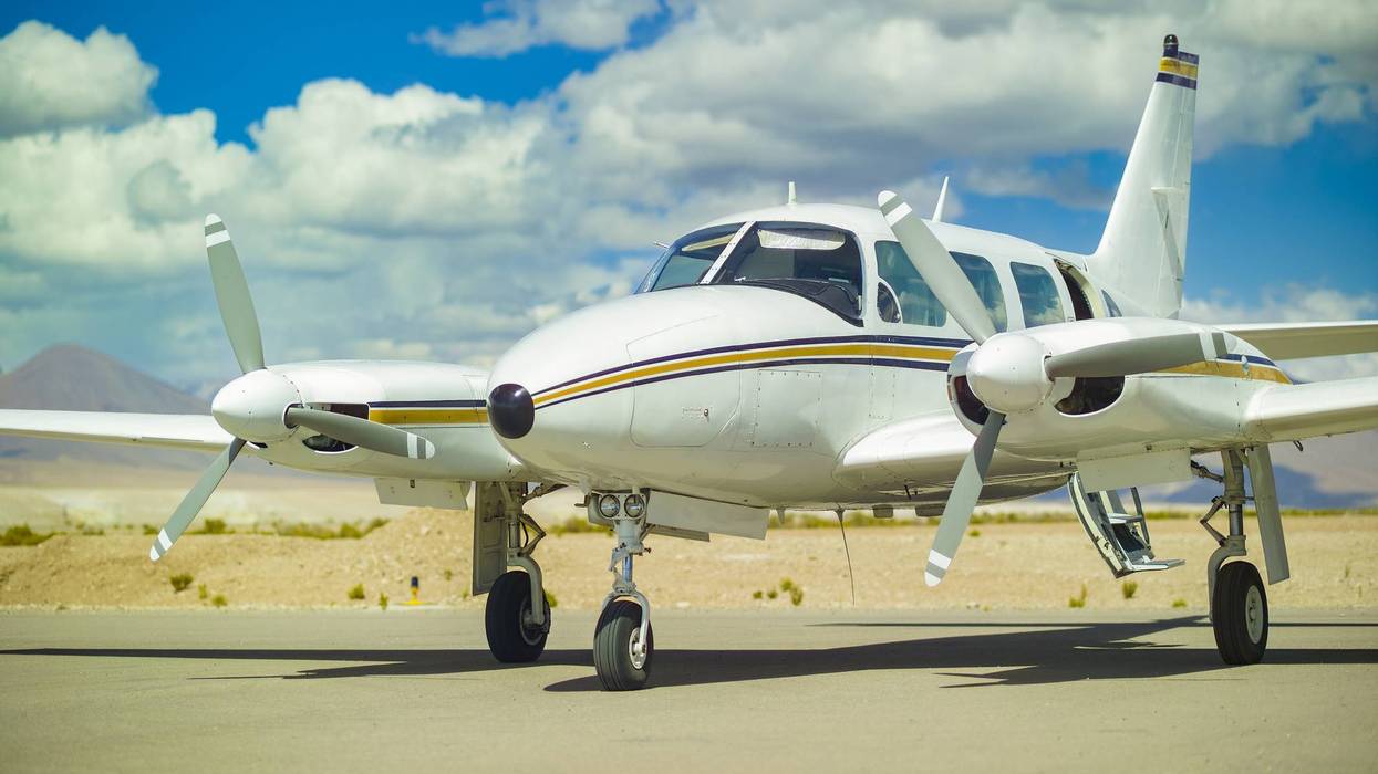 A close up of a Piper PA 31 Navajo, a light twin engine aircraft, on the tarmac under a blue sky.