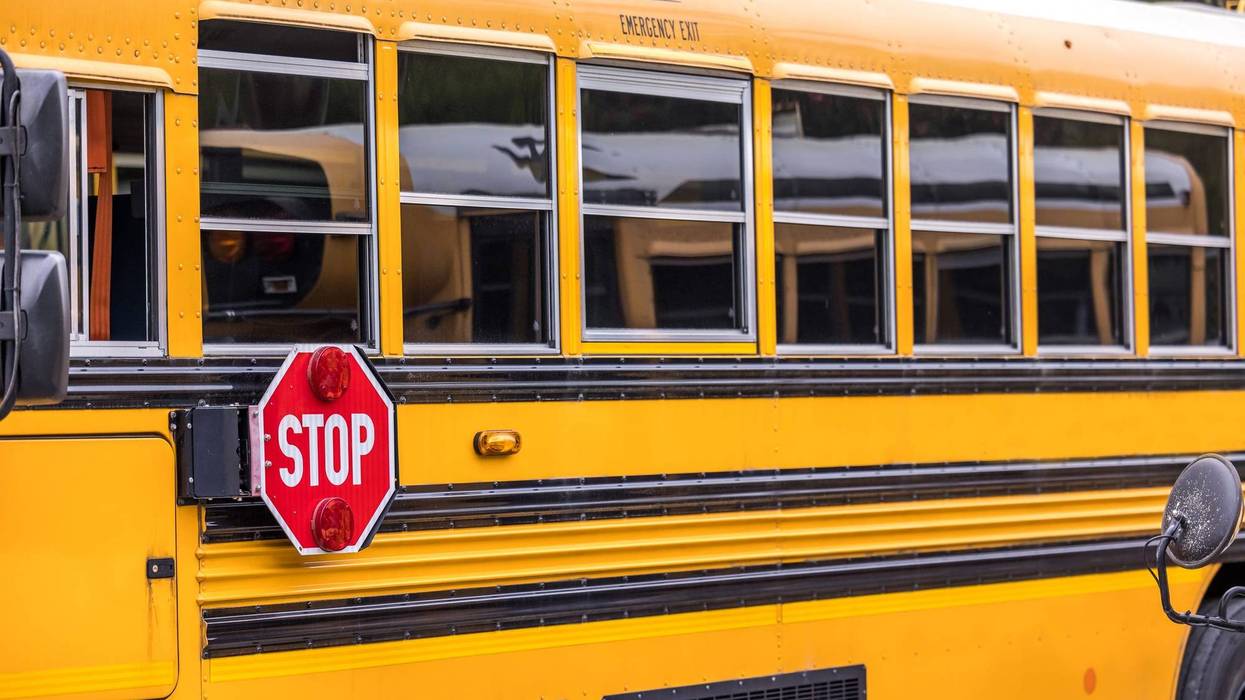 A close up of a yellow orange school bus with a red stop sign for back to school.