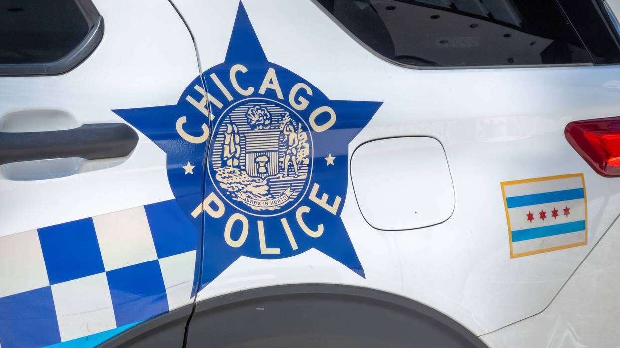 A close-up view of the Chicago Police Department's star-shaped emblem and the Chicago city flag on a white patrol car.