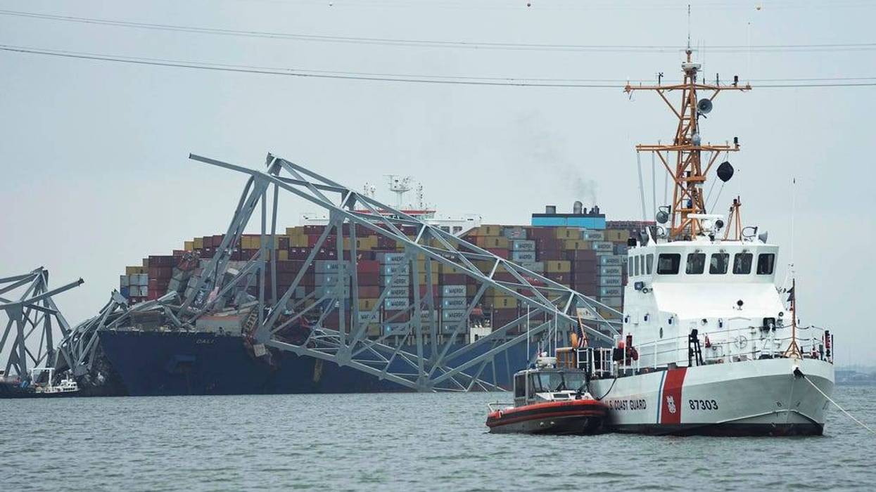 A Coast Guard cutter patrols in front of a cargo ship that is stuck under the part of the structure of the Francis Scott Key Bridge in Baltimore after the ship hit the bridge on Tuesday.