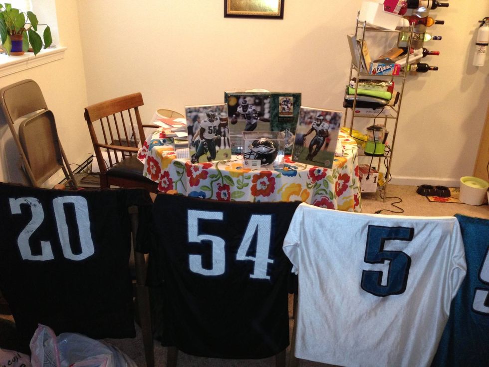 A collection of Eagles jerseys hung on chairs and further photos of past Eagles players on a table.