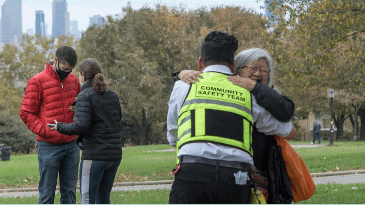 A community worker and elderly woman embrace