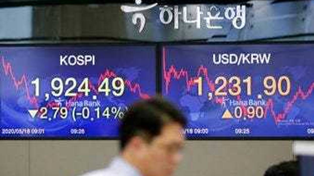 A currency trader walks near the screens showing the Korea Composite Stock Price Index (KOSPI), left, and the foreign exchange rate between U.S. dollar and South Korean won at the foreign exchange dealing room in Seoul, South Korea. (AP Photo/Lee Jin-man)