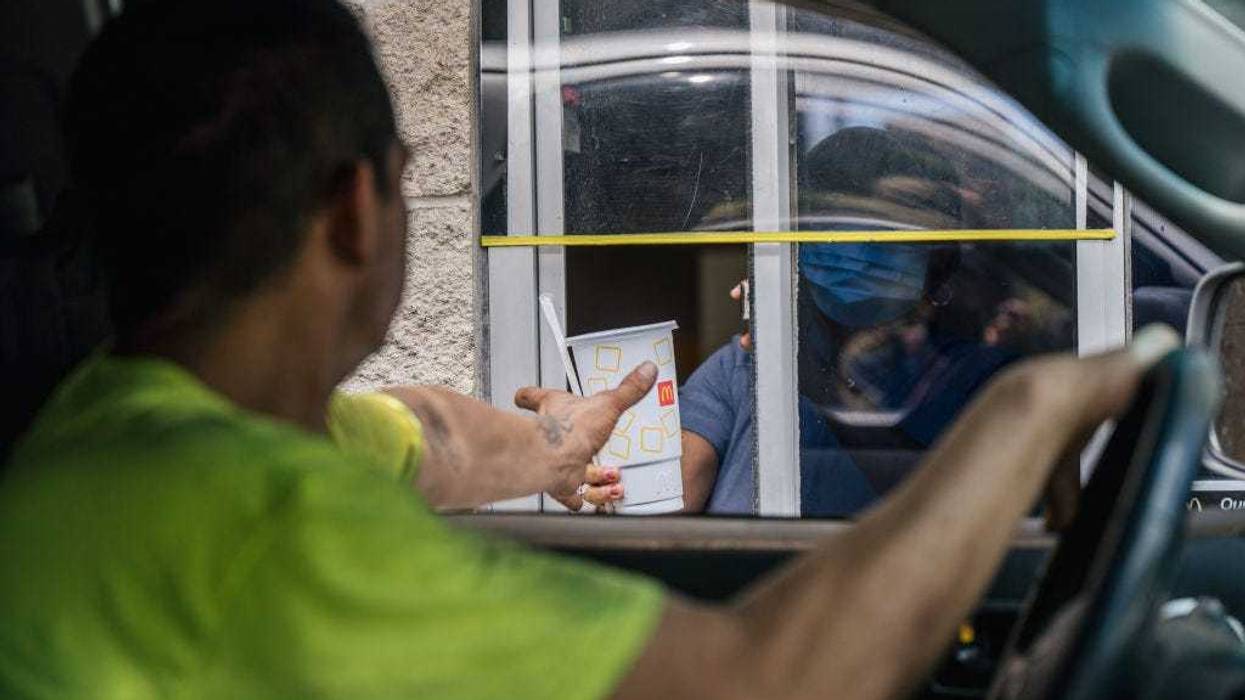A customer receives his food in a McDonald's drive-thru on July 28, 2021 in Houston, Texas. McDonald's corporation has said that its sales are surpassing pre-pandemic levels across the world as more of its dining rooms reopen after being shutdown during the pandemic. The company has also said that menu-price increases, larger to-go orders and its new crispy chicken sandwiches have largely contributed to boosted sales across the U.S. (Photo by Brandon Bell/Getty Images)