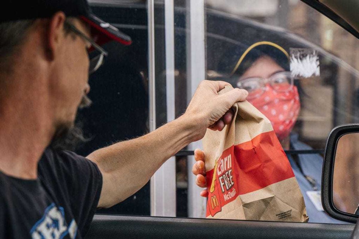 A customer receives his food in a McDonald's drive-thru on July 28, 2021 in Houston, Texas. McDonald's corporation has said that its sales are surpassing pre-pandemic levels across the world as more of its dining rooms reopen after being shutdown during the pandemic. The company has also said that menu-price increases, larger to-go orders and its new crispy chicken sandwiches have largely contributed to boosted sales across the U.S. (Photo by Brandon Bell/Getty Images)
