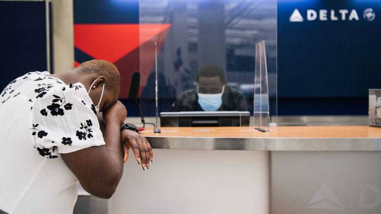 A customer rests their head down while speaking with a Delta Airlines employee at the George Bush Intercontinental Airport on January 13, 2022 in Houston, Texas. Due to the COVID-19 pandemic, Delta Airlines cancelled thousands of flights and lost $408 million in the final quarter of 2021. Delta has predicted that it will suffer one more quarterly loss before travel picks up in the spring and summer. (Photo by Brandon Bell/Getty Images)