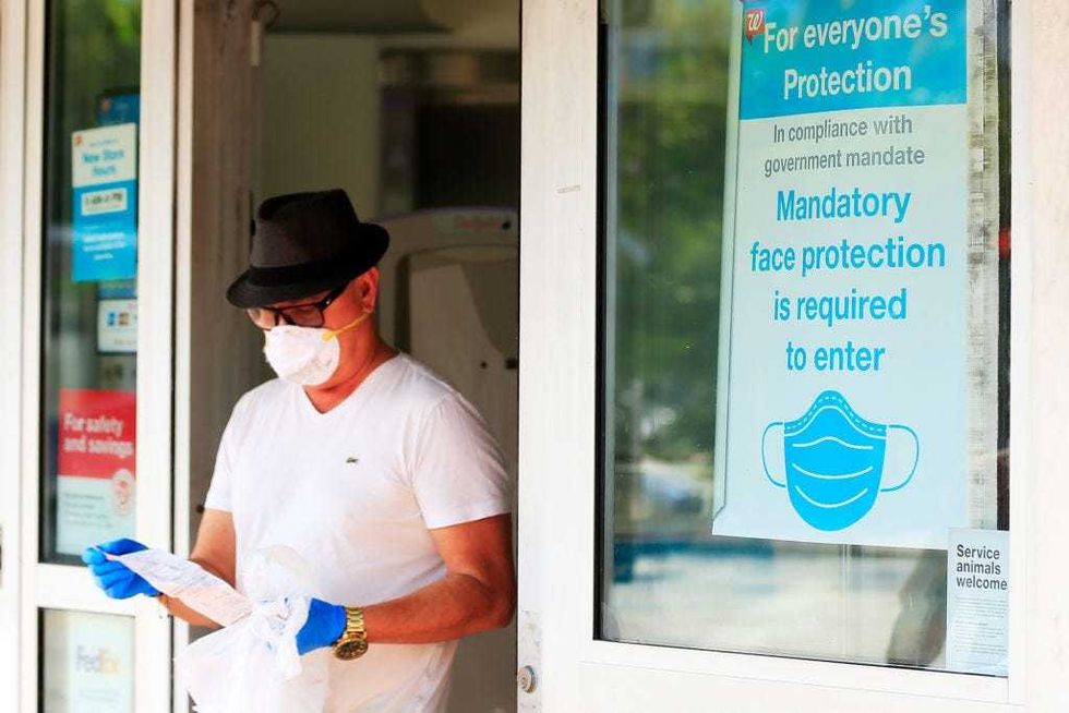 A customer wearing a face mask exits a Walgreens pharmacy
