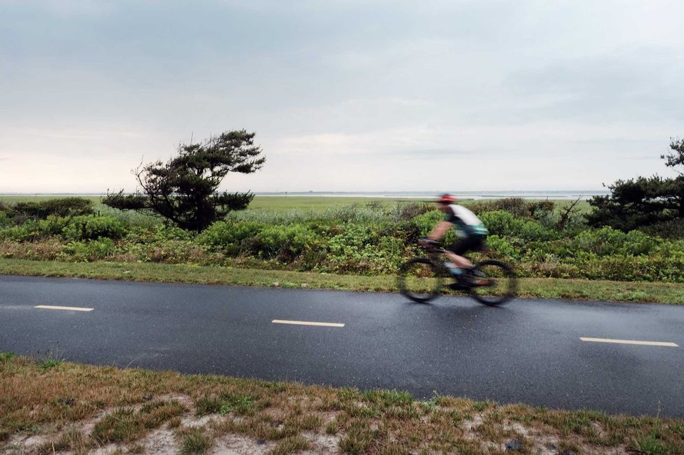 A cyclist rides down a path near Gilgo Beach on July 18, 2023. The remains of multiple victims were found in this area along Ocean Parkway