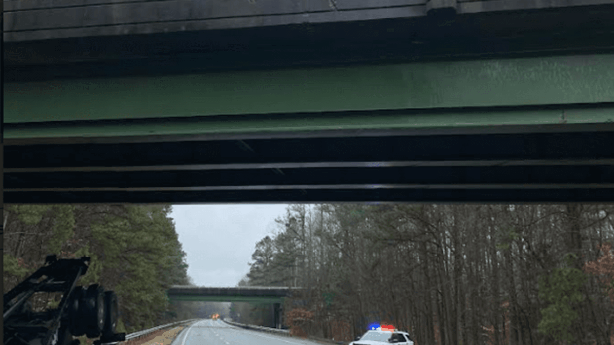 A damaged overpass, an overturned tractor-trailer, and a police car with its lights on