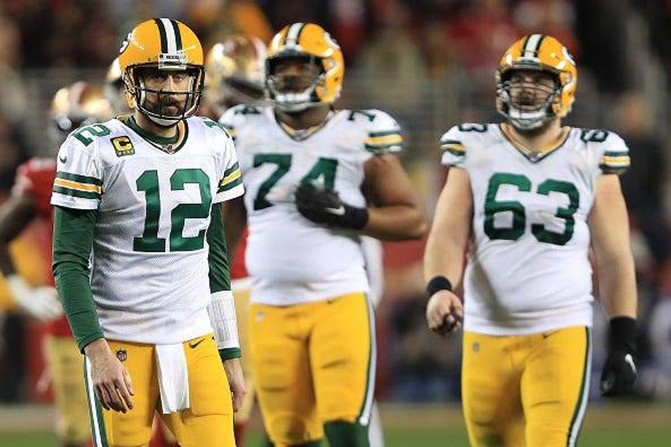 A dejected Aaron Rodgers walks off the field during a Packers game.