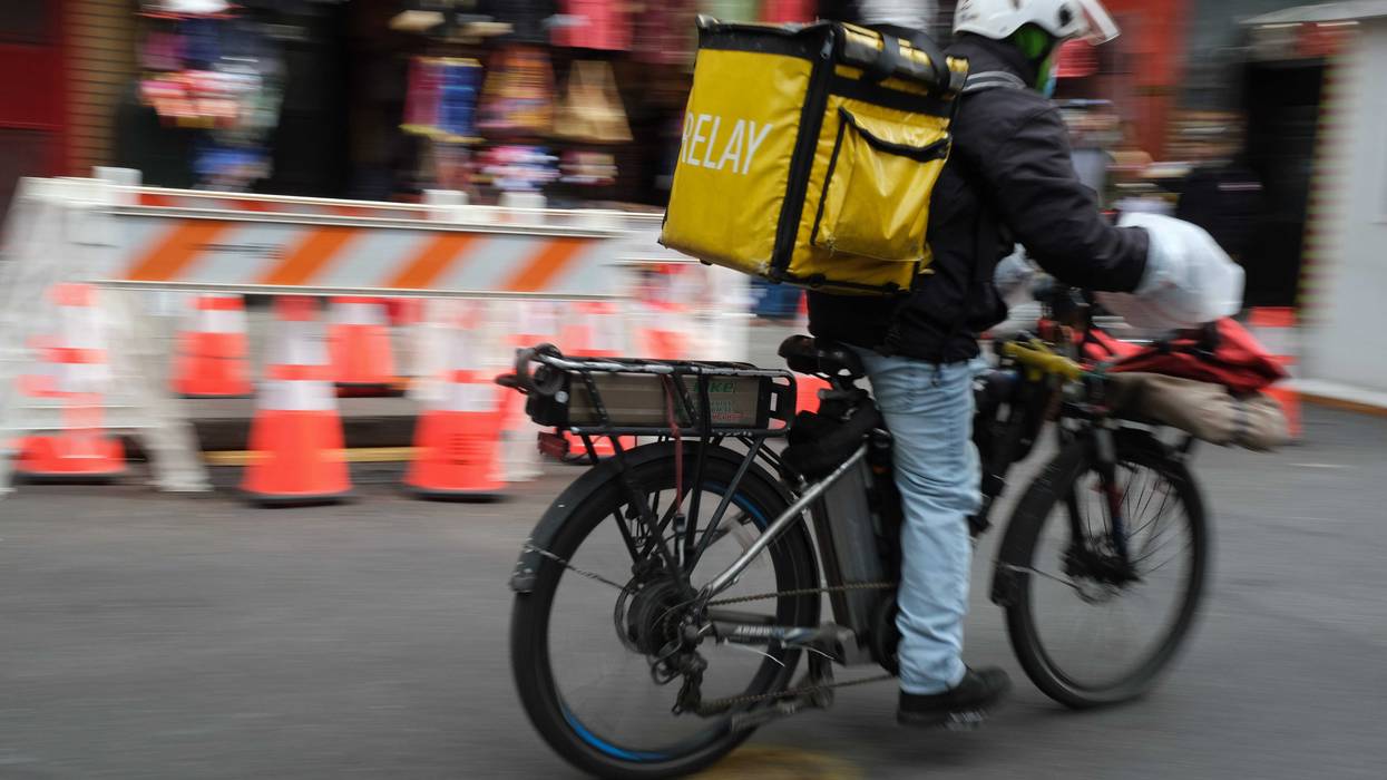 A delivery person rides an electric bicycle through the streets of Manhattan in New York City.