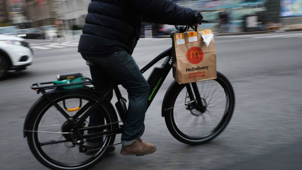 A delivery person rides an electric bicycle through the streets of Manhattan on November 15, 2022 in New York City.