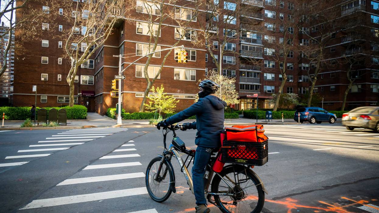 A delivery person with a DoorDash branded tote on his bicycle in Chelsea