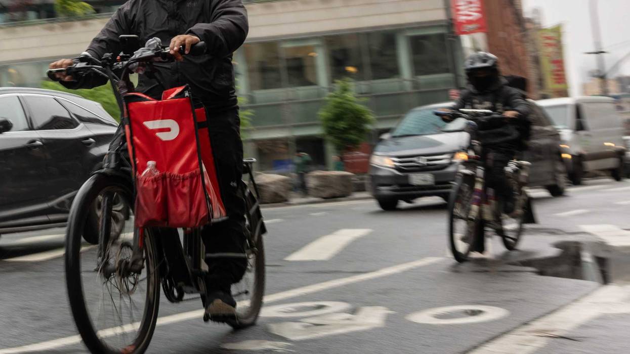 A delivery worker carries a DoorDash bag during a delivery in New York