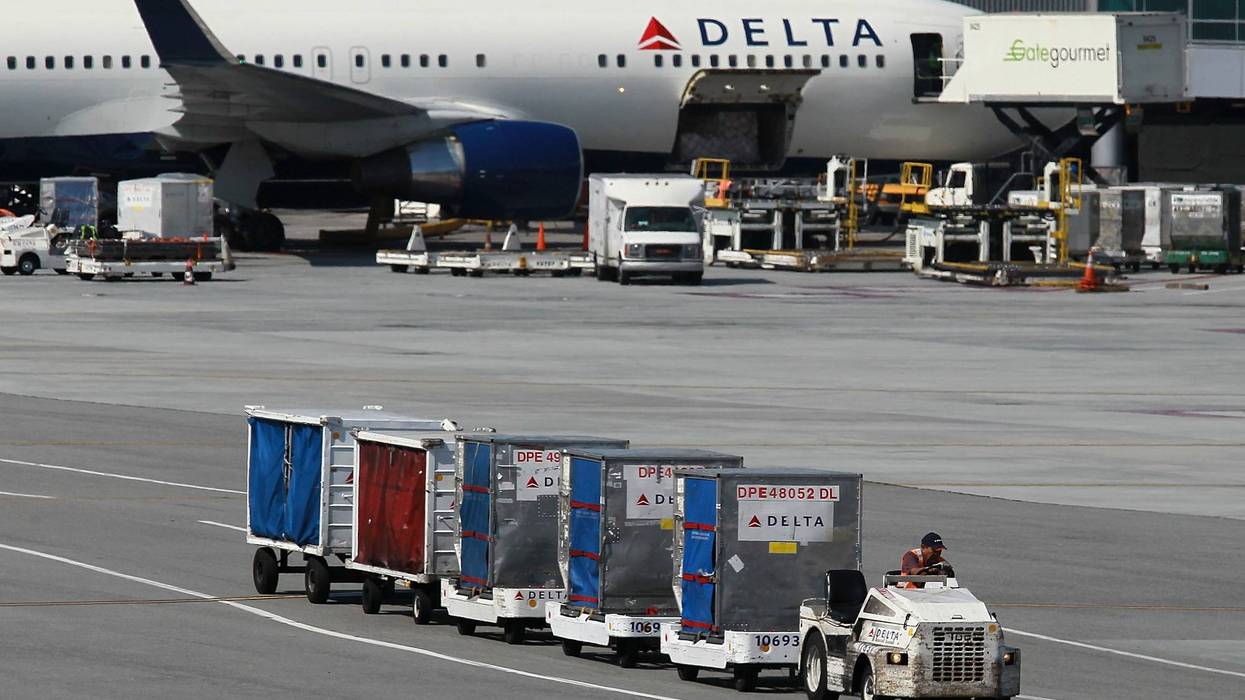 A Delta Airlines baggage cart drives by a Delta Airlines plane at San Francisco International Airport on July 27, 2011 in San Francisco, California.